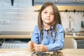 Portrait of a cute smiling girl preparing cookie dough in the kitchen. Little helper Royalty Free Stock Photo