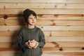 Portrait of cute smiling little boy with piggy bank on wooden background. Child with money in green hat. Royalty Free Stock Photo