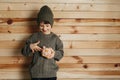 Portrait of cute smiling little boy with piggy bank on wooden background. Child with money in green hat. Royalty Free Stock Photo