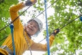 Portrait of cute smiling little boy walk on a rope in an adventure rope park on summer vacation. Child in tourist equipment on a Royalty Free Stock Photo