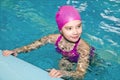 Portrait of cute smiling little girl child swimmer in pink swimming suit and cap in the swimming pool Royalty Free Stock Photo