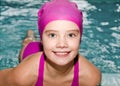 Portrait of cute smiling little girl child swimmer in pink swimming suit and cap in the swimming pool Royalty Free Stock Photo