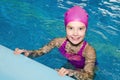 Portrait of cute smiling little girl child swimmer in pink swimming suit and cap in the swimming pool Royalty Free Stock Photo