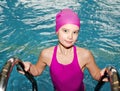 Portrait of cute smiling little girl child swimmer in pink swimming suit and cap in the swimming pool Royalty Free Stock Photo