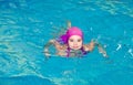 Portrait of cute smiling little girl child swimmer in pink swimming suit and cap in the swimming poo Royalty Free Stock Photo