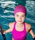 Portrait of cute smiling little girl child swimmer in pink swimming suit and cap in the swimming pool Royalty Free Stock Photo