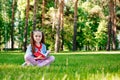 Portrait of Cute Smiling Little Girl Sitting On Grass And Reading Book In Park Royalty Free Stock Photo