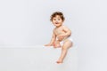 Portrait of cute smiling toddler boy, baby in diaper sitting isolated over white studio background. Happy child Royalty Free Stock Photo