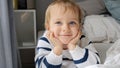 Portrait of cute smiling toddler boy with blue eyes lying in bed at morning Royalty Free Stock Photo