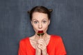 Portrait of cute surprised girl eating sweet lollipop