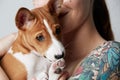 Portrait of a cute tattooed beautiful woman hugging and kissing her little puppy basenji dog. Love between dog and owner