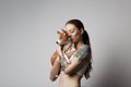 Portrait of a cute tattooed young woman hugging and kissing her little puppy basenji dog. Love between dog and owner Royalty Free Stock Photo