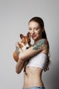 Portrait of a cute tattooed young woman hugging and kissing her little puppy basenji dog. Love between dog and owner Royalty Free Stock Photo