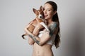 Portrait of a cute tattooed young woman hugging and kissing her little puppy basenji dog. Love between dog and owner Royalty Free Stock Photo