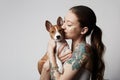 Portrait of a cute tattooed young woman hugging and kissing her little puppy basenji dog. Love between dog and owner Royalty Free Stock Photo