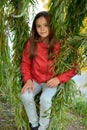 Girl in the leaves of a weeping willow Royalty Free Stock Photo