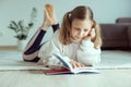 Portrait of cute teen girl reading book on floor in room at home Royalty Free Stock Photo