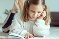 Portrait of cute teen girl reading book on floor in room at home Royalty Free Stock Photo