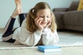 Portrait of cute teen girl reading book on floor in room at home Royalty Free Stock Photo