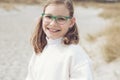 Portrait of cute teenage girl in glasses smiling on bech with dunes on Baltic sea
