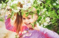 Portrait of cute teenager girl looking at camera surrounded by blooming white cherry branches in garden. Royalty Free Stock Photo