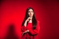 Portrait cute thinking teen girl wearing stylish red costume over red background wall looking away Royalty Free Stock Photo