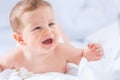 Portrait of cute toddler boy lying on bed. Newborn child in bedroom. Baby lies on his tummy raises the head and crying Royalty Free Stock Photo