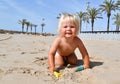 Portrait of a cute toddler boy playing with the sand at the beach in sunlight. Royalty Free Stock Photo