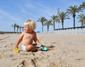 Portrait of a cute toddler boy playing with the sand at the beach in sunlight. Royalty Free Stock Photo