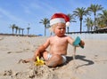 Portrait of a cute toddler boy wearing Santa hat playing on the beach. Christmas vacation with kids concept Royalty Free Stock Photo