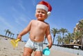 Portrait of a cute toddler boy wearing Santa hat playing on the beach. Christmas vacation with kids concept Royalty Free Stock Photo