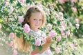 Portrait of a cute toddler girl outdoor in a rose garden smelling the flowers