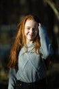 Cute twelve year old girl with fiery red hair posing in the pine park for a photoshoot Royalty Free Stock Photo