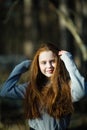 Portrait of cute twelve year old girl with fiery red hair posing in the pine park Royalty Free Stock Photo