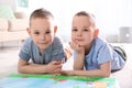 Portrait of cute twin brothers with book on floor Royalty Free Stock Photo