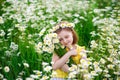 Portrait of a cute village girl in a wreath and a bouquet of flowers on a chamomile field. A child in a blooming daisy meadow. She Royalty Free Stock Photo