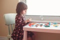 White Caucasian preschooler girl playing plasticine playdough indoors at home