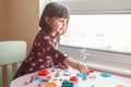 White Caucasian preschooler girl playing plasticine playdough indoors at home