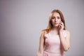 Portrait of cute woman in pink dress talking on smartphone on grey background with copy space. Modern technology, communications,