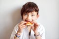 Portrait of cute 7 years old hungry short haired girl in white kimono eating pizza after hard on-line karate taekwondo training. Royalty Free Stock Photo