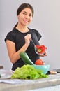 Portrait of cute young asian girl smiling while cooking salad with fresh vegetables in kitchen interior at home Royalty Free Stock Photo