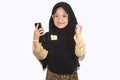 Portrait of cute A young asian little girl 6-7 years old muslim, wearing hijab, show face expression using a smart phone or