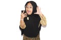 Portrait of cute A young asian little girl 6-7 years old muslim, wearing hijab, show face expression using a smart phone or