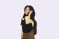 Portrait of cute A young asian little girl 6-7 years old muslim, wearing hijab, show face expression using a smart phone or