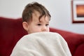 a Portrait of a cute young boy watching tv whith his safety blanket