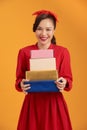 Portrait of a cute young girl in dress holding stack of present boxes isolated over orange background Royalty Free Stock Photo