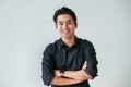 Portrait of a cute young and handsome Asian man in casual shirt fold his arms with confidence and pose to camera with warm smile