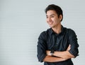 Portrait of a cute young and handsome Asian man in casual shirt fold his arms with confidence and pose to camera with warm smile