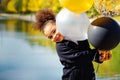 Portrait of a cute young little black girl playing with balloons in the Park. Black and gold silver balloons in the hands of a Royalty Free Stock Photo