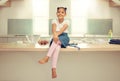 Portrait of a cute young mixed race girl sitting on the kitchen counter with an apron and smiling. Little hispanic girl Royalty Free Stock Photo